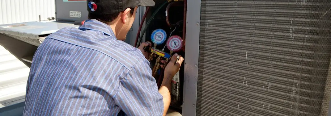 HVAC technician servicing a condenser unit in Krum